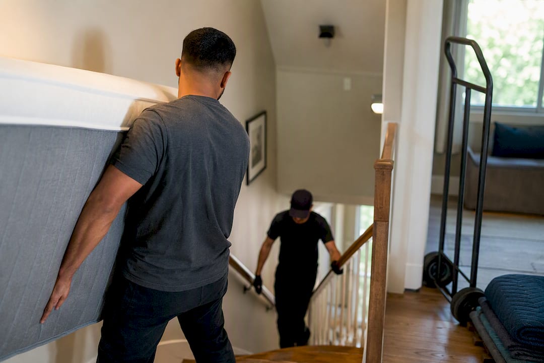 Crew removing mattress down residential stairs