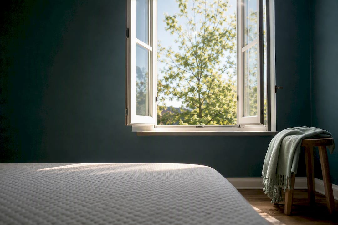 Open bedroom window beside mattress edge